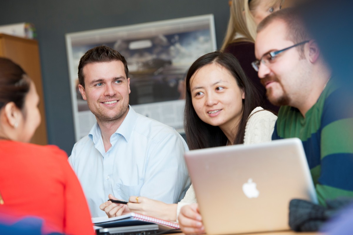 Four Surrey Executive MBA students sitting around a laptop