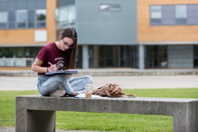 Student sitting on bench reading