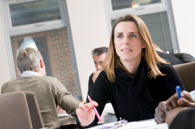 Female University of Surrey EMBA student with two male students in the background