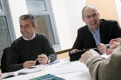 Two male University of Surrey EMBA students smiling in a classroom setting