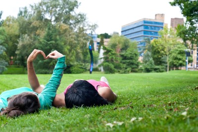 Students on grass with hands in hearts
