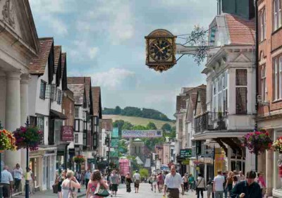 Guildford High Street looking towards the Hogs Back, with people shopping and walking in the road.