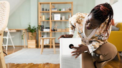A woman leans over her sound system in her living room.