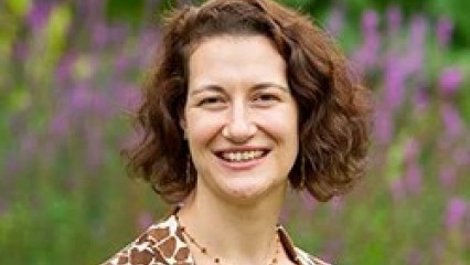 head and shoulders picture of Dr Cooper, smiling against blurred outdoor backdrop