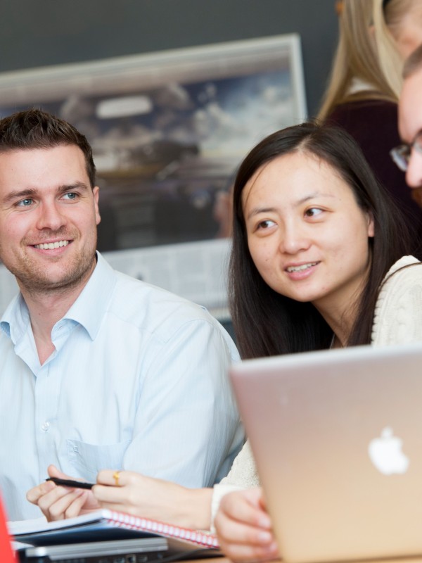 Four Surrey Executive MBA students sitting around a laptop