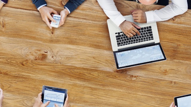 View from above of people using laptops, tablets and phones