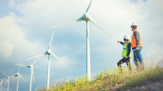 Civil engineers standing by wind turbines
