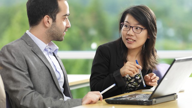 A man and woman talking whilst sat at a desk