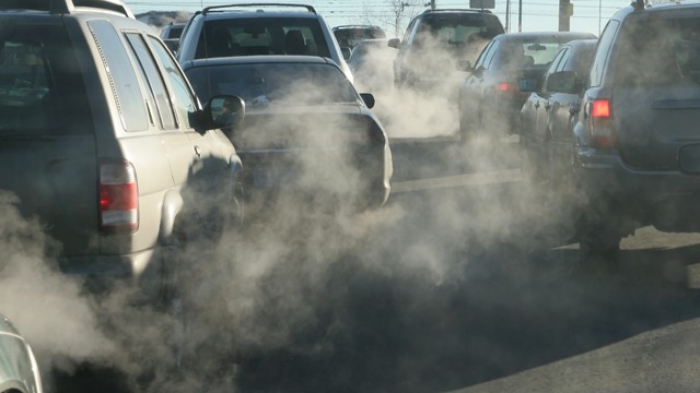 Cars in traffic with fumes coming out their exhausts