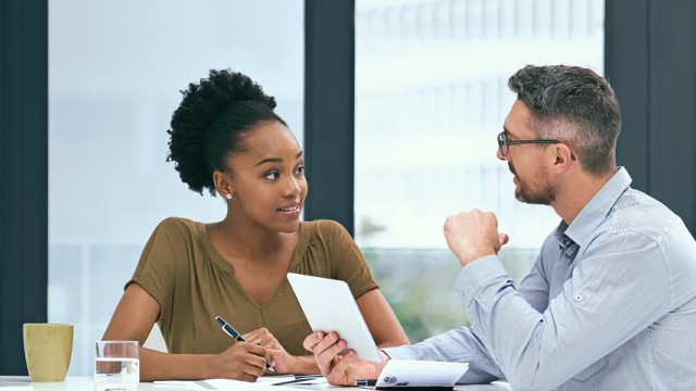 Male and female talking around desk