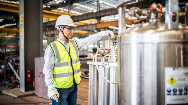 worker operating a gas tank in a factory