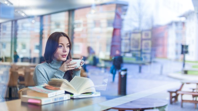 Student sat with work and a coffee