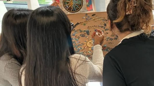 three women from behind doing a jigsaw puzzle
