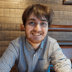 Samuel is a white man with brown hair wearing a striped shirt smiling at the camera.