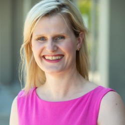 A photo of a blond woman wearing a bright pink dress