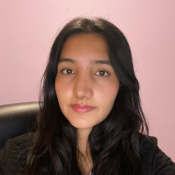 Monique is sitting down, smiling at the camera.