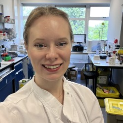 Picture of Dr Clarke wearing a white lab coat in the laboratory.
