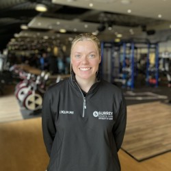 Demi is smiling at the camera, wearing a Surrey Sports Park jumper