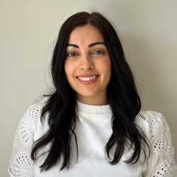 Nat stands in front of a white backdrop, smiling at the camera