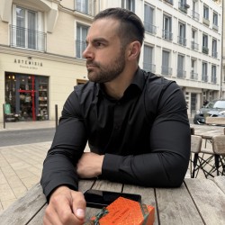 Marc Russo looking to his right in a black shirt sat at a table outside a Parisian cafe.