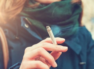 A lady holding a lit cigarette in her right hand