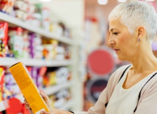 Lady reading health information on a packet of food in the supermarket