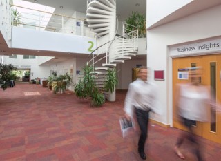 An image of the Surrey Business School foyer with people walking through it