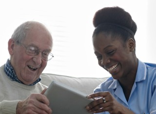 Elderly man using a tablet alongside nurse