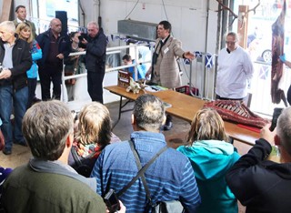 Group of people looking at cured meat on a hook