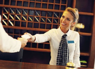 A lady serves a hotel guest on reception