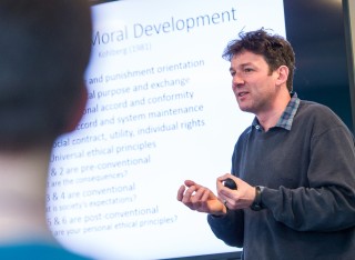 A man giving a lecture in front of a whiteboard