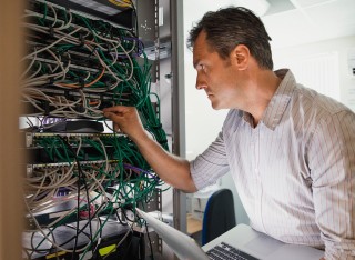 IT technician standing next to data bank