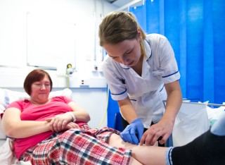 Female nursing student applying dressing to a leg wound