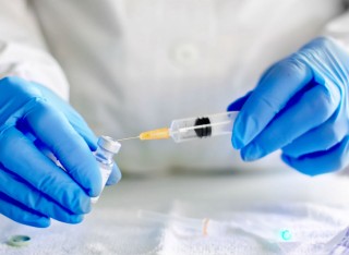 Scientist putting syringe in vile