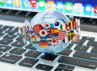 World globe with several country flags around it, sitting on top of a laptop keyboard