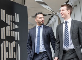 Two students in suits standing by an IBM sign