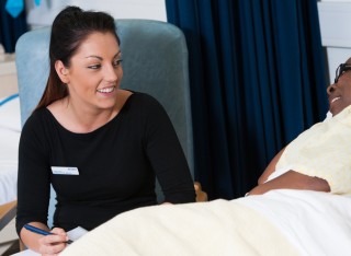 Mental health nursing student speaking to patient in a hospital bed