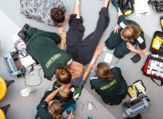 Birdseye view of trainee paramedics providing treatment to a medical manikin