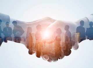 Handshake with visual of people working together within this