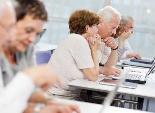 A group of elderly people take part in a computer class