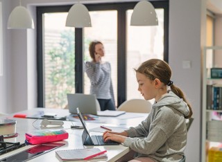 Girl studying at home in the kitchen whilst mum works from home