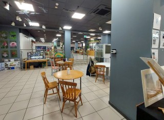 Chairs, tables and displays in a lit room, which is ZERO. On a vertical wall a small air quality monitor can be seen