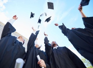 Graduates celebrating by throwing hats into air