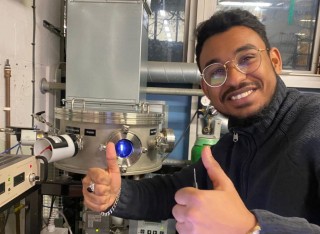 Moe Ahmed smiles and gives two thumbs up in Surrey's hi-tech Propulsion Laboratory