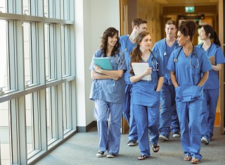 Group of medical students in scrubs walking through open doors on a hospital corridor