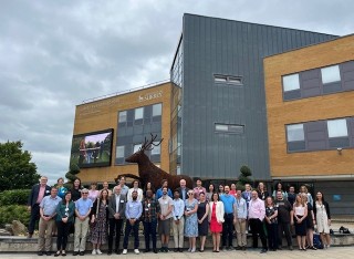 Group of people outside Rik Medlik building in front of Stag sculpture