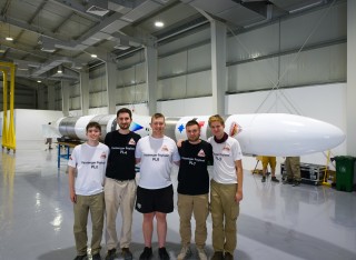 Students in Oman with a rocket behind them