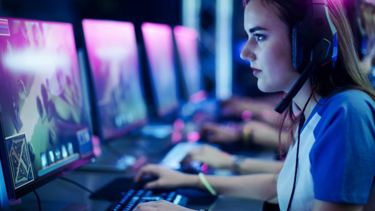Girl playing video games on a computer wearing a headset