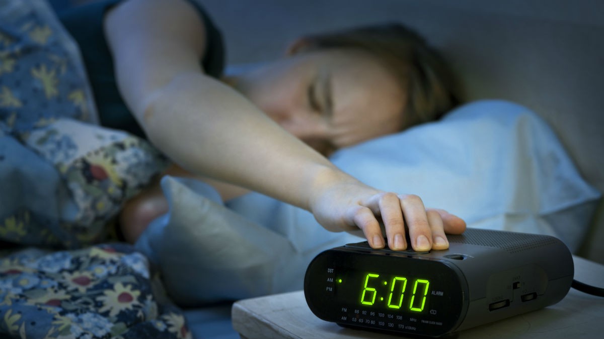 Person reaching to turn off their alarm clock