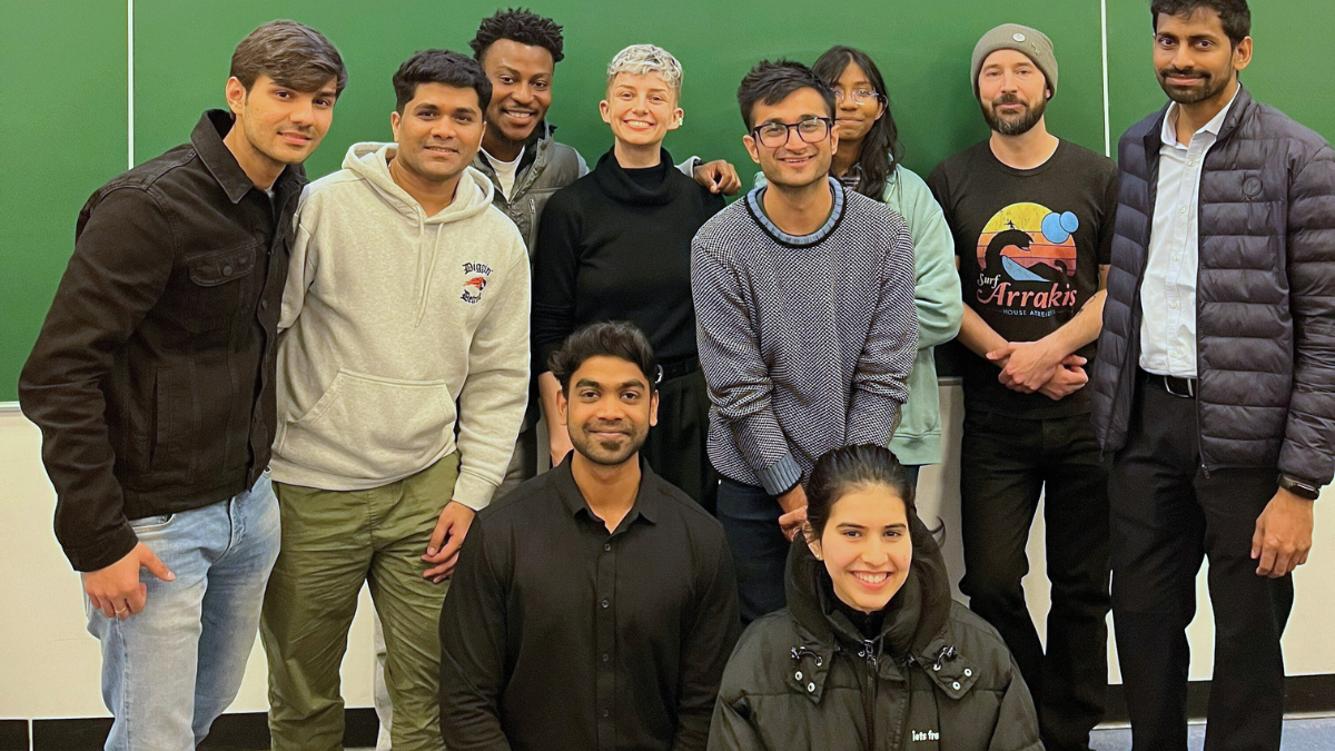 A group of students pose for a picture in front of a lecture screen